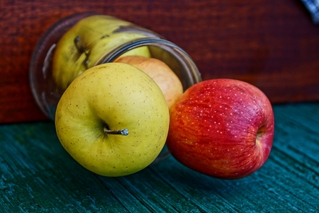 glass jar with ripe apples at the green wallの写真素材
