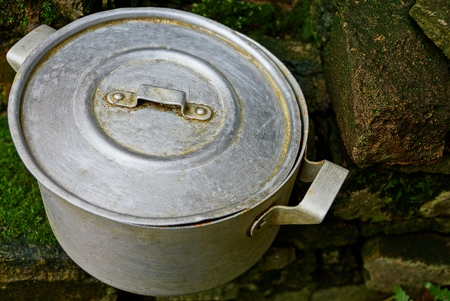 Gray old saucepan covered with lid on green bricksの写真素材