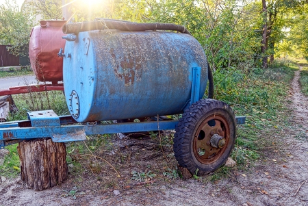 two old rusty barrels on wheels on the streetの写真素材
