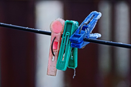 three colored clothespins in the hoarfrost on the wireの写真素材