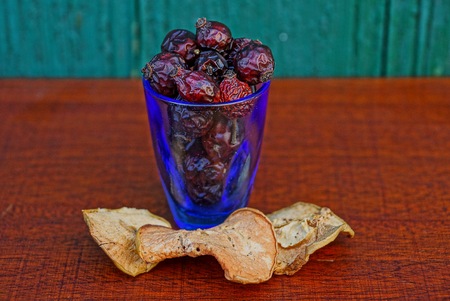 dry hips of a dogrose and pieces of a dry apple in a wine-glass and on a tableの写真素材