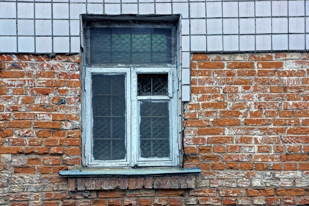 An old window with a lattice on the brick wall of the house