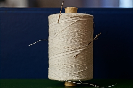 large spool of white thread with needlesの写真素材