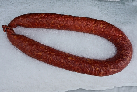 salami sausage ring on white snowの写真素材
