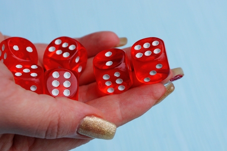 red dice in a pile on a hand on a blue backgroundの写真素材