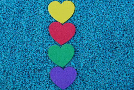 a row of colored hearts on blue sandの写真素材
