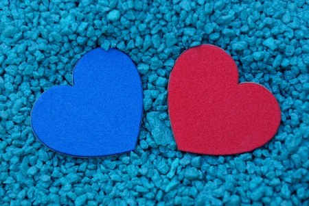 two colored hearts in a pile of small blue stonesの写真素材