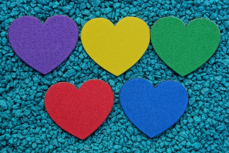 a row of colored hearts on blue small stonesの写真素材