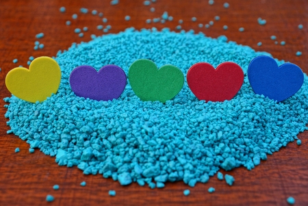a row of colored hearts on blue sand on a red table
