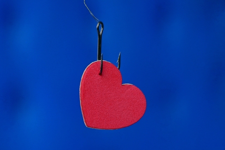 red heart on a fishing hook on a blue backgroundの写真素材