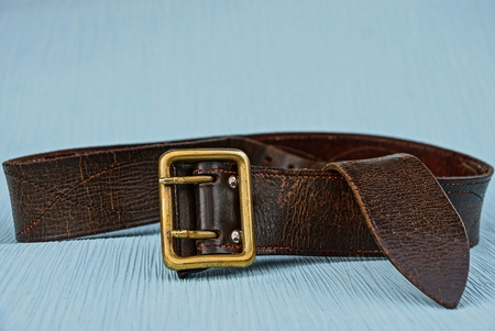 brown belt with a copper buckle on a blue table