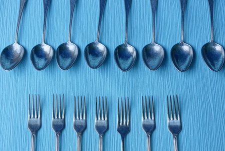Iron gray spoons and forks on a blue table