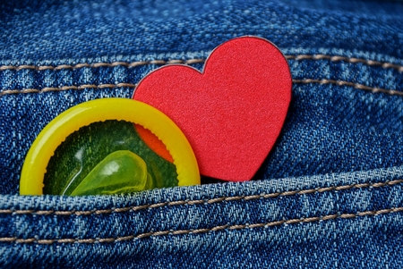 yellow condom and red heart in blue coton pants pocketの写真素材