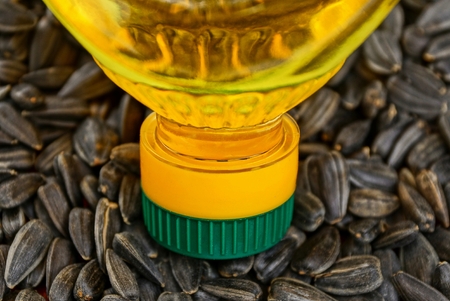 transparent bottle with sunflower oil on a pile of sunflower seedsの写真素材