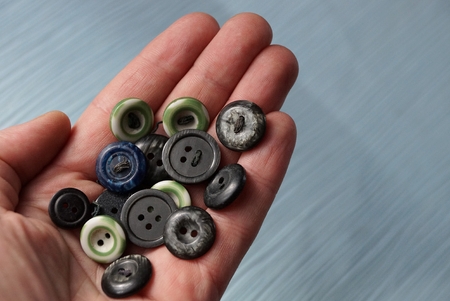 a bunch of old colored buttons on an open palm above the tableの写真素材