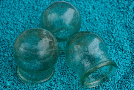 three old glass medical jars on blue sandの写真素材