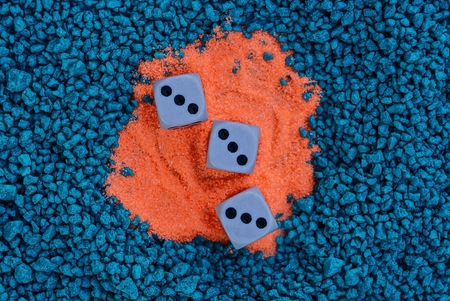 three game dice on red sand and blue stonesの写真素材