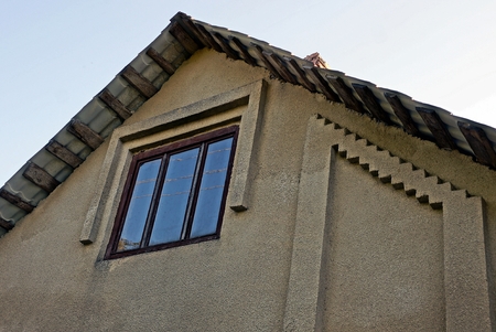 Part of a gray building with an attic window