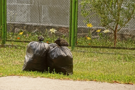 Closed garbage bags with garbage on the lawnの写真素材