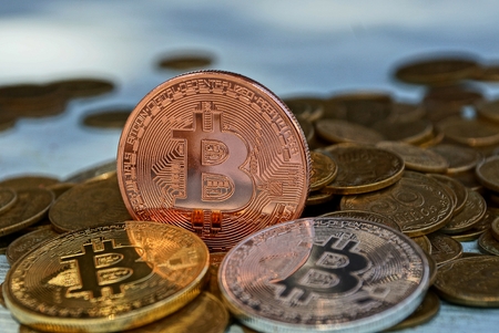 large coins bitcoin on a pile of small yellow coinsの写真素材