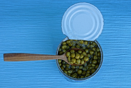 green peas in a tin can and a wooden spoonの写真素材