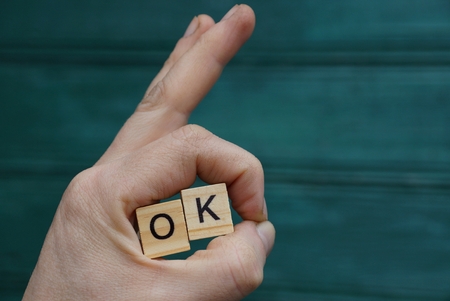 hand gesture and wooden letters with the word ok on a green backgroundの写真素材