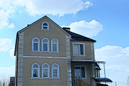 facade of a large brown house with windows against the sky and cloudsのeditorial素材