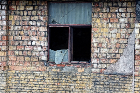 a broken old window on the wall of a brick houseの写真素材