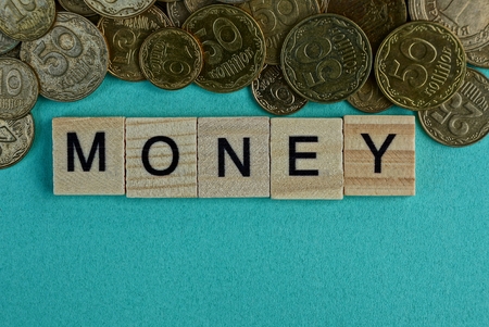 Word money from wooden letters on a green background with small coinsの写真素材