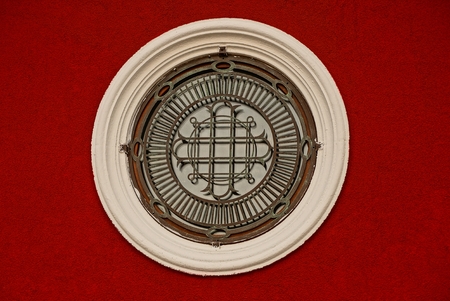 gray round window with a lattice on a red wallの写真素材
