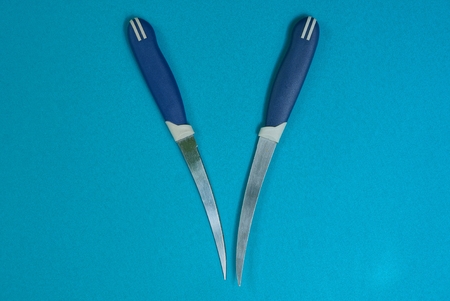 two thin knives on a blue backgroundの写真素材