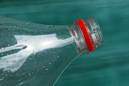 part of an empty plastic bottle with a neck on a green backgroundの写真素材