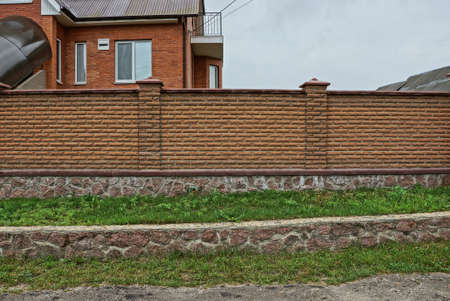 brown fence of brick and stone in green grass on the streetのeditorial素材