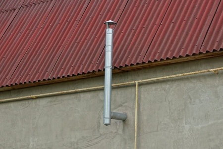iron pipe hood on the wall of a house under a roofの写真素材