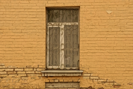 old window with an iron grill on a brown wallの写真素材