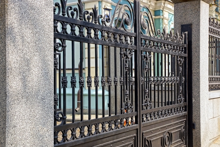 part of the black gate of steel bars and concrete pillars