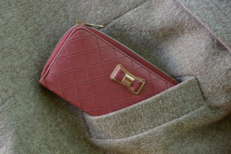red purse in a gray pocket of woolen clothes