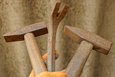 two old brown hammers and a steel rusty hammer in handの写真素材