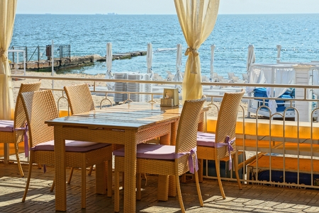 Part of the summer terrace of the restaurant with brown chairs and a table with curtains on the...