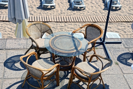 brown table and chairs on the open terrace by the beach with sand and sun bedsの写真素材