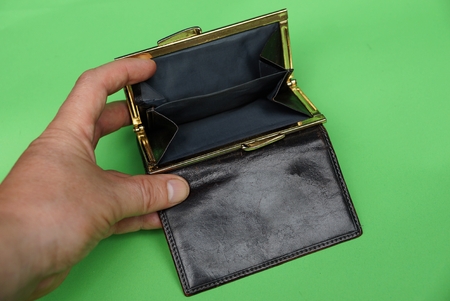 open brown empty purse in hand on a green background