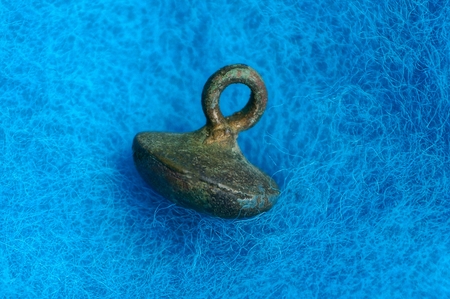 small gray copper button on blue woolen fabric