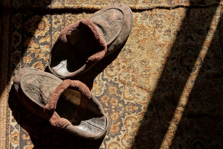 Two old brown slippers on a rug in the sunlightの写真素材