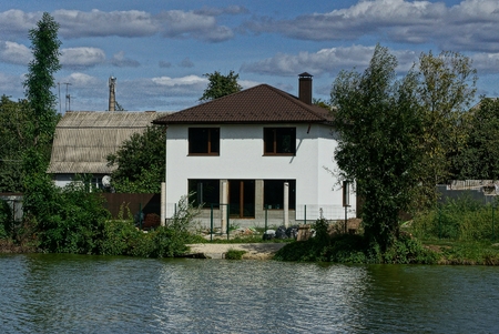 large private white house with windows near the water on the shore of the reservoirのeditorial素材
