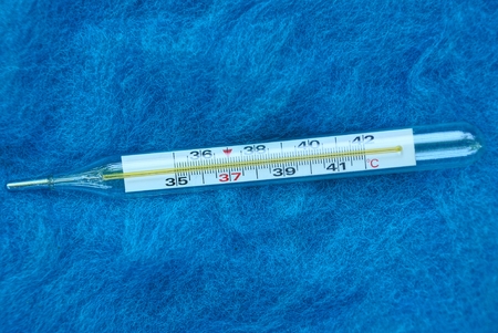 glass medical thermometer on blue woolen fabricの写真素材