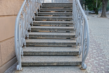 gray concrete steps of the stairs with handrails near the wall of the house on the sidewalkの写真素材