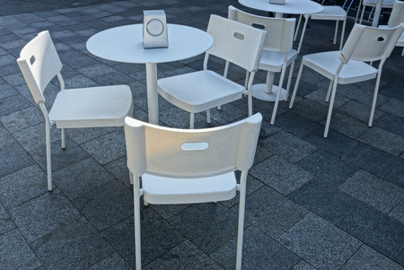 white plastic tables and chairs on the gray sidewalkの写真素材