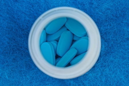 blue pills in a white bottle on woolの写真素材