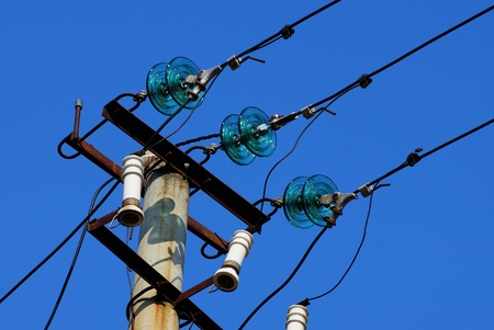 part of a concrete pillar with wires against a blue skyの写真素材