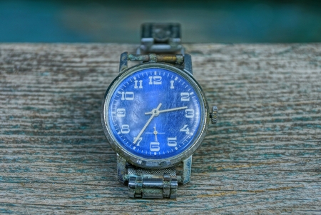 blue old shabby watch with a metal strap on a gray table